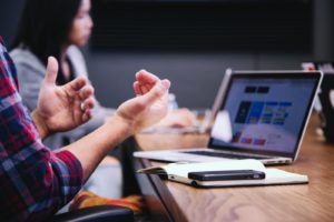 Man gesturing while using laptop in background