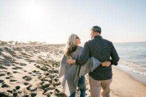 Older man and woman hugging side by side on the beach