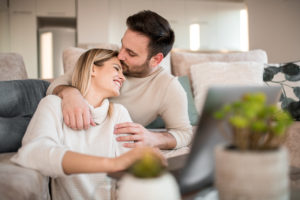 Smiling couple hugging and using laptop