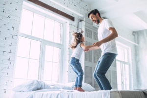 Man and child jumping on bed