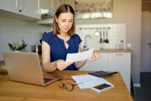 Woman looking at documents and laptop in kitchen