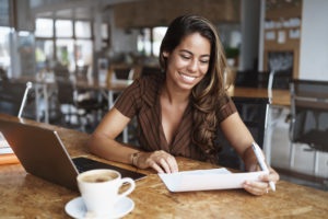 Woman in a cafe looking at a document and smiling