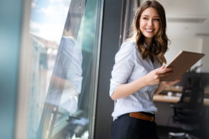Business woman sitting on windowsill while looking at tablet