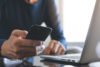 Man looking at smart phone and laptop
