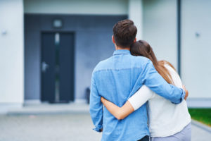 Man and woman hugging side by side in front of home