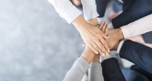 A group of people putting their hands in the middle one on top of the other