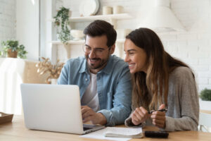 Man and woman looking at laptop smiling together