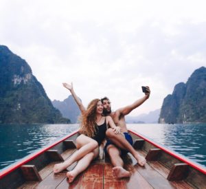 Man and woman sitting in a boat taking a selfie
