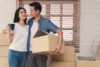Young Asian couple standing around moving boxes in new home