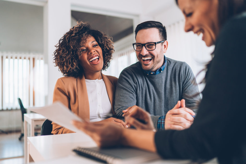 a happy couple meeting with their lender to discuss cash-out refinance vs. HELOC options