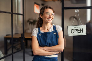Business woman smiling next to open sign