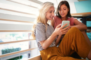 Two young women using Zelle on their smartphone