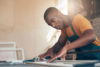 Black man cutting wood wearing an apron in his hardware store