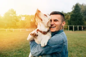 Smiling man holding his dog outside