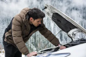 Man fixing his engine in the snowy mountains.