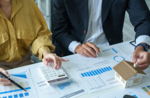 Bank officer explaining interest rates on home equity loans to a customer, looking at documents and calculator.