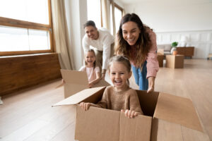 Family playing with small children, pushing daughters in boxes at home.