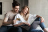 Happy couple using laptop while holding credit card
