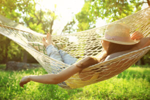 Young woman resting in a hammock outside in a green garden.