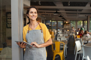 Smiling waitress at a restaurant holding a digital tablet.