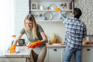 Couple cleaning up their kitchen wearing orange gloves.