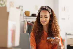 Woman holding UCCU card and typing in card information into computer to make a purchase.