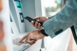Man using ATM pinpad while holding phone