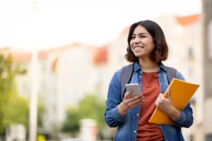 Student on phone holding notebook