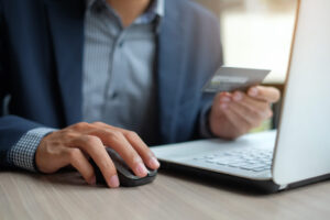 Businessman holding a credit card and using a laptop.