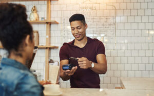 Young waiter processing a credit card from a customer in a cafe.