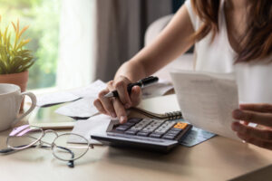 Woman using a calculator looking at receipts and other documents.