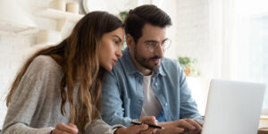 Couple sitting in a home working together on a laptop computer.