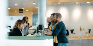 Man and woman talking to an employee at a front desk.