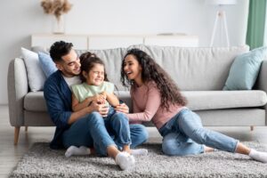 Family of three in living room laugher with their young child