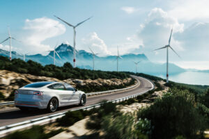 car driving on a road passing windmills and mountains.