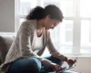 Woman smiling on couch while using iPad