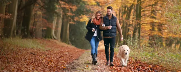 Man and Woman walking with Dog in Fall Leaves